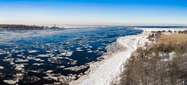 Havadan kış manzarası, Daugava Nehri 'nin Riga yakınlarında Baltık Denizi' yle buluştuğunu gösteriyor. Donmuş Mangalsala deniz feneri, kayan buz kütleleri, karlar, ağaçlar, kum tepeleri ve açık gün ortası ışığı..