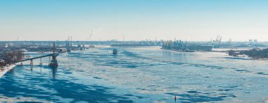 Hava görüntüsü, Riga Tersanesi 'nin oradaki donmuş Daugava Nehri' ni gösteriyor. Mavnalar, buz kütleleri ve Mangalsala deniz feneri alanı. Letonya 'da soluk bir kış gökyüzü altında yığınlar ve kubbeler..