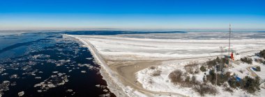 Hava görüntüsü Daugava Nehri 'nin Mangalsala, Riga' da Baltık Denizi 'yle buluştuğunu gösteriyor. Mangalsala deniz fenerine, kayan dalgalara, deniz buzuna ve karlı direğe giden buzlu bir dalgakıran..