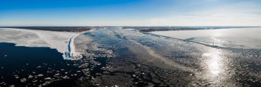 Hava görüntüsü, donmuş Daugava Nehri 'nin Riga' da Baltık Denizi ile buluştuğunu gösteriyor. Buz kütleleri kış güneşi altında tersaneden geçerken ikiz dalgalar kırmızı Mangalsala Deniz fenerini çerçeveledi.