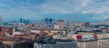 Bratislava, Slovakya 'nın hava manzarası tarihi çatıları, yeşil kaplamalı eski belediye binası kulesini, kilise kulelerini ve aydınlık parçalı bulutlu gökyüzünün altındaki modern cam yükseltileri gösteriyor..