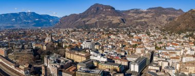 Bolzano, İtalya 'nın hava manzarası Katedral kulesini, kırmızı kiremitli çatıları, üzüm bağlarını, çiftlik evlerini, demiryollarını ve açık kış ışığı altında karlı Dolomite sırtlarını gösteriyor..