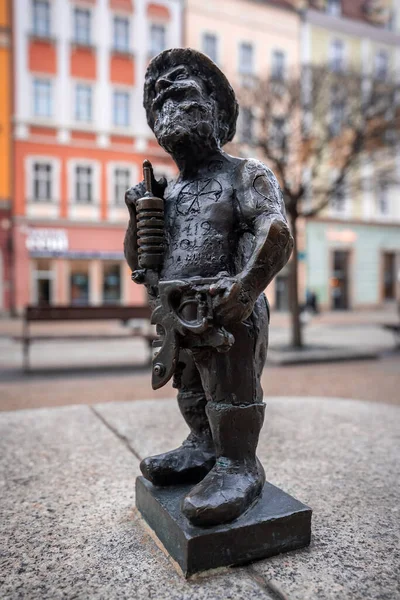 Polonya 'nın Wroclaw kentinde elinde matkap ve büyük bir anahtarla bronz bir cüce heykeli bir kaidede duruyor. Bulutlu bir günde Pastel cepheleri bulanıklaşır, alçak bir açıdan çekilir..