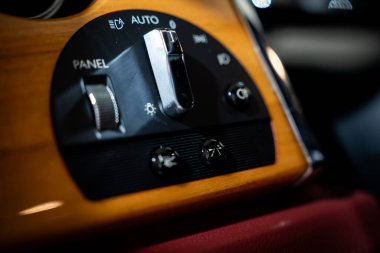 Bir Rolls Royce Phantom 'un far ve panel kontrolleri koyu kırmızı deri üzerinde parlak bir burl ahşap üzerinde oturur, siyah bir düğme, düğmeler, düğmeler ve düğmeler üzerinde krom düğmeli.
