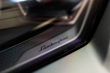 Dar bir makro, bir atölyede, Revuelto 'nun farına kazınmış Lamborghini senaryosunu gösteriyor. Altıgen desen, fırçalanmış metal, yumuşak yansımalar ve sığ odak, teknik bir atmosfer ekler..