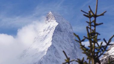 İsviçre, Zermatt yakınlarındaki Matterhorn 'un hava görüntüsü, rüzgarlı kar ve alçak sis bulutları zirvenin etrafında kıtır ışık ve derin mavi bir gökyüzü altında dönüyor..