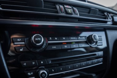 İç görünüm BMW X5 iklim ve infotainment kontrollerini gösteriyor, AUTO çevirisi, SYNC ve A C tuşları, koltuk ısıtıcı simgeleri, radyo ayarları 1 'den 8' e ve tehlike anahtarı.