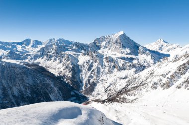 Havadan bakıldığında San Domenico, İtalya 'da kayakçılar, kaldırma hatları, kar tepeleri, sivri kayalıklar ve vadide kış boyunca modern bir çatı katı tarzı otel görülüyor..