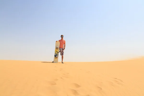 Joven parado en una duna con tabla de arena — Foto de Stock