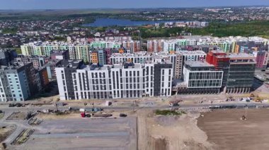 Aerial view of modern residential buildings, colorful apartments with urban landscape, construction site and green environment in city.