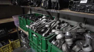 Metal otomotiv süspansiyon kolları yeşil kasalarda, kullanılmış araba parçalarının raflarda ve etiketlerde depolanması.