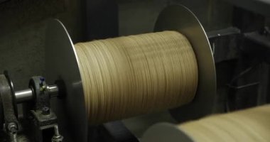 Endüstriyel makaralı bej iplik, yakın plan kablo veya tüp imalat tesisinde sarılı..
