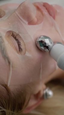 Nemlendirici jel maskeli ultrasonik bir cihaz kullanarak profesyonel yüz bakımı prosedürü..