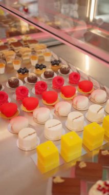 Fırın vitrininde sergilenen renkli modern hamur işleri ve kremalı kekler..