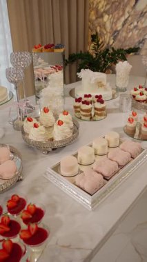 Zarif pastalar, pastalar ve çiçek desenli lüks bir tatlı masası. Tatil için dekore edilmiş. Modern bir iç mekanda şık bir tasarım..