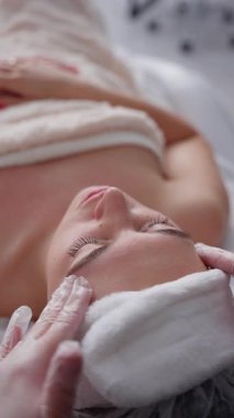 Güzellik uzmanı, güzellik salonunda çalışan genç bir kadın için yüz bakımı prosedürleri uyguluyor..