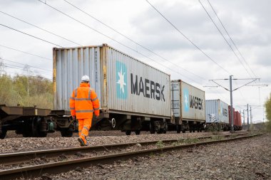 DONCASTER, İngiltere - 4 Nisan 2021. İngiltere demiryolu ağındaki Maersk nakliye konteynır yük trenini ihracat veya ithalattan önce denetleyen bir demiryolu işçisi