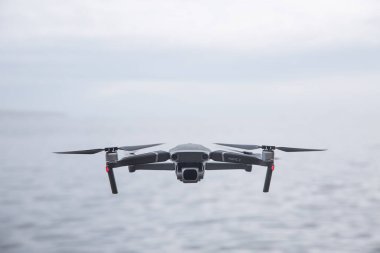 CORNWALL, İngiltere - 29 Haziran 2021. Bir DJI Mavic Pro 2 insansız hava aracı suyun üzerinde uçuyor ve fotokopi alanı ile kameraya bakıyor.