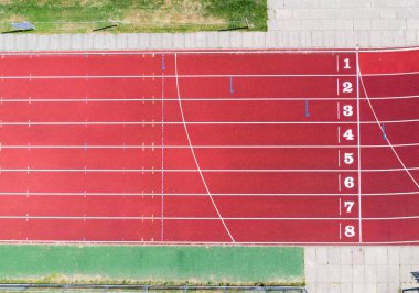 Pist bitiş çizgisinde koşan bir atletizmin hava görüntüsü şeritleri ve numaraları gösterir