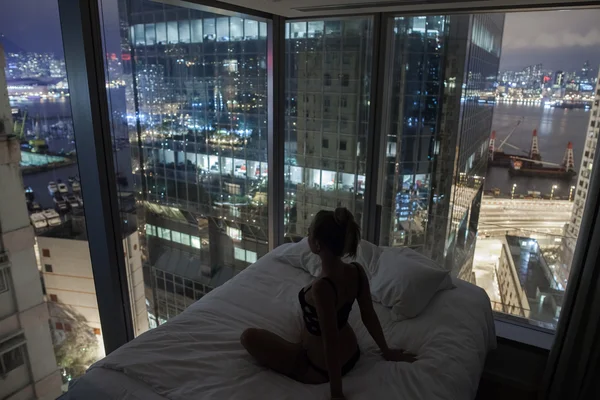 Joven mujer atractiva disfrutando de la vista del paisaje urbano en la cama Fotos De Stock Sin Royalties Gratis