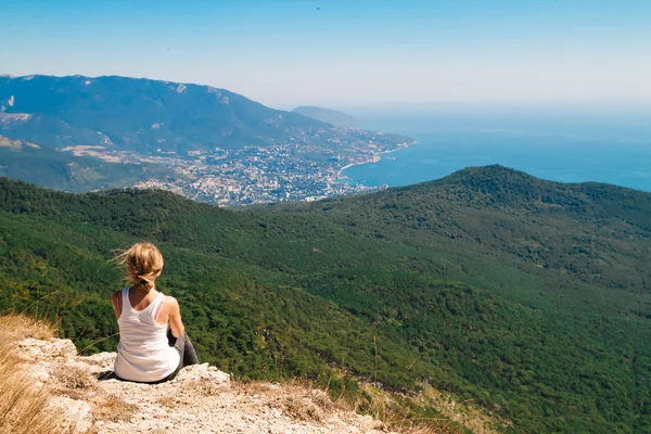 Blond meisje met broodje kapsel op de rand van een klif — Stockfoto