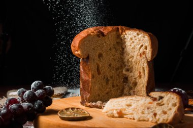 Koyu arkaplanda Noel pastası panettonu ve Noel süslemeleri. Arkaplanda kar taneleri.