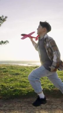 Çekilen görüntüler, kameralar paralel giderken, gece ışığı açık manzarayı sararken çocuğun sahada coşkuyla koştuğunu gösteriyor. Dikey.