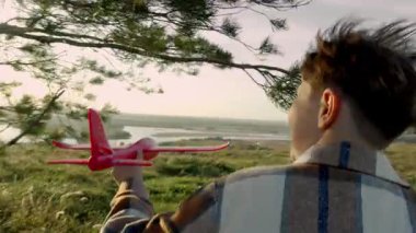 El kamerası, çocuğu uçakla batan güneşe doğru koşarken çeker. Yükselen çimenler ve parlayan gökyüzü. Açık alanda uçtuğunu hayal ederken coşkulu hareketler..