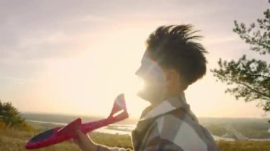 Sahne, ekose gömlekli bir çocuğun gün batımında kırmızı planörle yarıştığı, kamera onun parıltılı manzaranın yanındaki hareketlerini izlerken dinamik hareketi izlediği bir sahne. Ağır çekim. Portre.