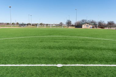 Güneşli bir günde şehir parkında suni çimlerle bir futbol kalesinin manzarası.