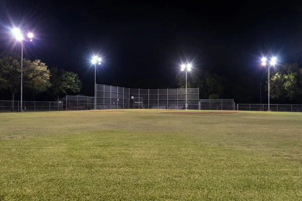 Campo de béisbol vacío por la noche con las luces encendidas —  Fotos de Stock