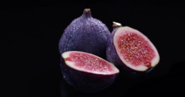 Siyah arka planda izole edilmiş su damlaları olan taze incirler.