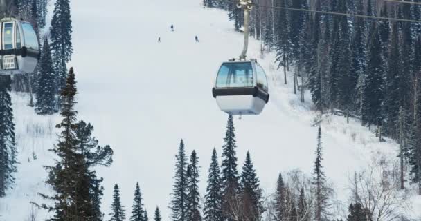 Cabines d'ascenseur dans une station de ski de montagne. Le mouvement des remontées mécaniques dans une montagne enneigée d'hiver. Sheregesh, Russie. — Video