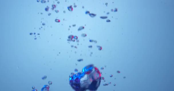 Air bubbles colored in blue and red rising up on blue background. — ストック動画