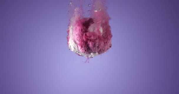 Színes fürdőbomba zuhan a tiszta vízbe a kék háttér ellenére. Lassított felvételen, RED kamerával — Stock videók