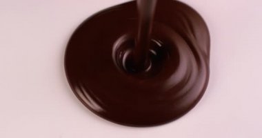 Beyaz bir yüzeye ağır çekimde erimiş koyu kaliteli çikolata dökülüyor. RED kamerayla çekildi.
