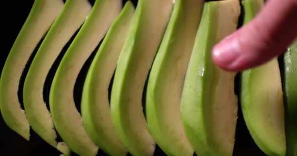 Maschio mano impila fette di avocado fresco. Pezzi di avocado grezzi da vicino. Girato al rallentatore con telecamera ROSSA. — Video Stock