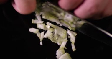 Aşçı erkek elleri siyah ayna yüzeyinde beyaz soğan kesiyor. Kırmızı kameradaki görüntüyü kapat.