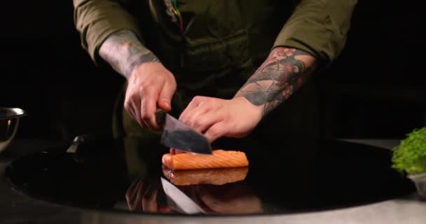 Шеф-повар мужских рук режет сырого лосося на черной поверхности. Снимок крупным планом на камеру RED. — стоковое видео