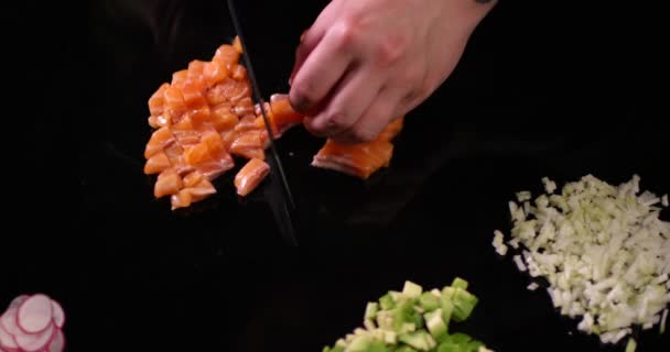 Шеф-повар мужских рук режет сырого лосося на черной поверхности. Снимок крупным планом на камеру RED. — стоковое видео
