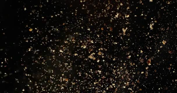 Black pepper grains sprinkles over camera on black background. Shot in slow motion with RED camera. — Stock Video