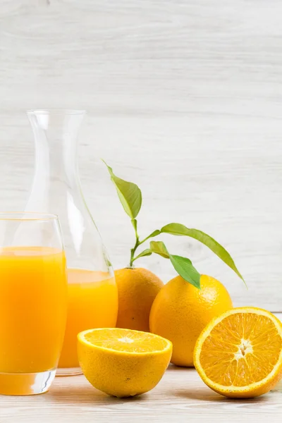 Апельсини і склянка соку на дерев'яному столі — стокове фото