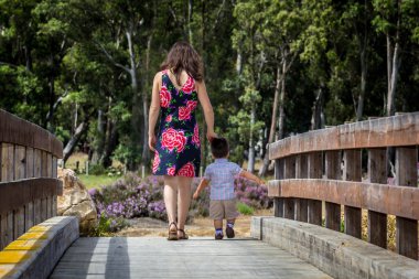 Anne ve oğlu bir tahta köprüden geçerken