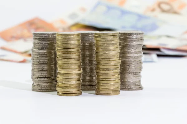 Monedas de 2 y 1 euros apilados y billetes en euros — Foto de Stock
