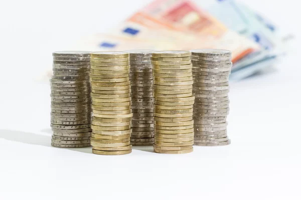 Monedas de 2 y 1 euros apilados y billetes en euros — Foto de Stock