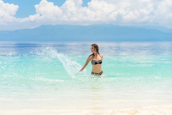 Jonge Europese vrouw in bikini met goed humeur spatten en dansen in mooie tropische kalme zee onder een bewolkte hemel van de zachte — Stockfoto