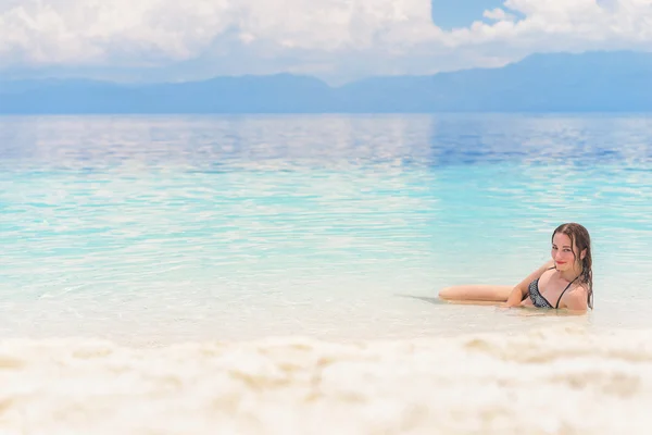 Jonge Europese vrouw in bikini met goed humeur en wegkwijnen blik ligt in mooie tropische kalme zee onder een bewolkte hemel van de zachte — Stockfoto