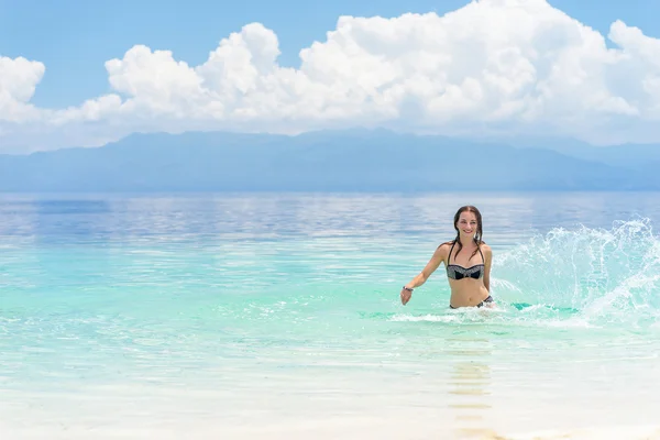 Jonge Europese vrouw in bikini met goed humeur spatten en dansen in mooie tropische kalme zee onder een bewolkte hemel van de zachte — Stockfoto