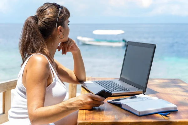 Młode ładne kobiety pisarz freelancer pracę z Notatnik laptop i telefon infront niebieski tropikalne morze — Zdjęcie stockowe