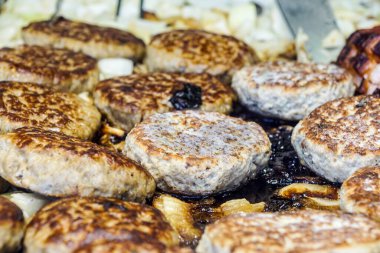 Bir hamburgerci sıcak bir barbeküde pişiriyor.